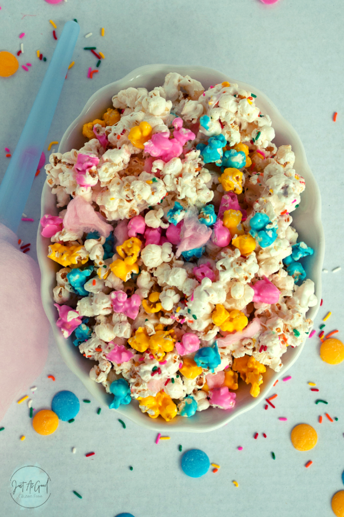 A whole bowl of cotton candy popcorn with pink, blue and yellow candy melts