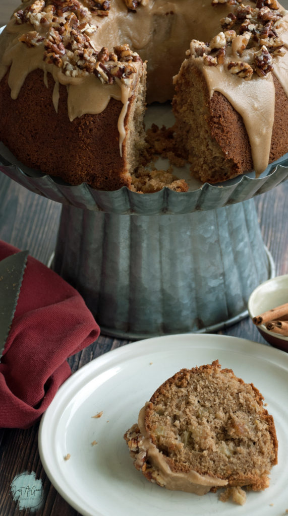 A slice of Gluten Free Apple Cake with brown sugar and cinnamon frosting and pecan praline topping