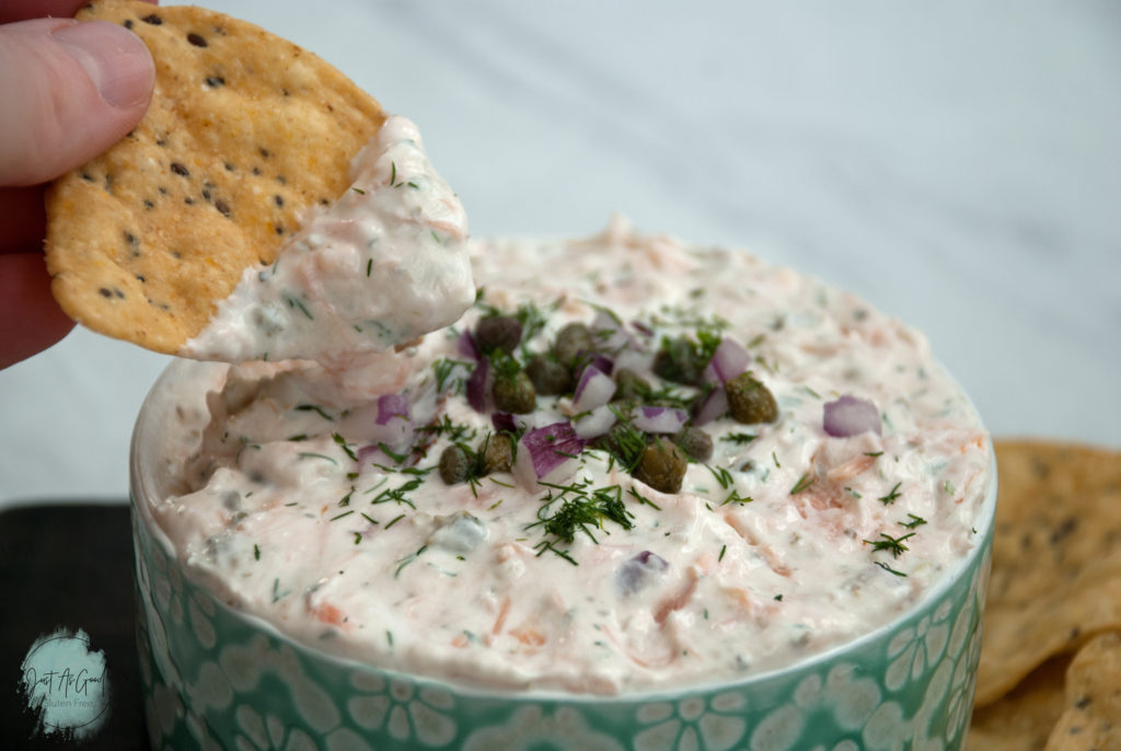 tortilla chip dipped into bowl of smoked salmon dip