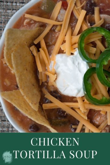 bowl of chicken tortilla soup with cheddar cheese, tortilla chips, sour cream and jalapenos