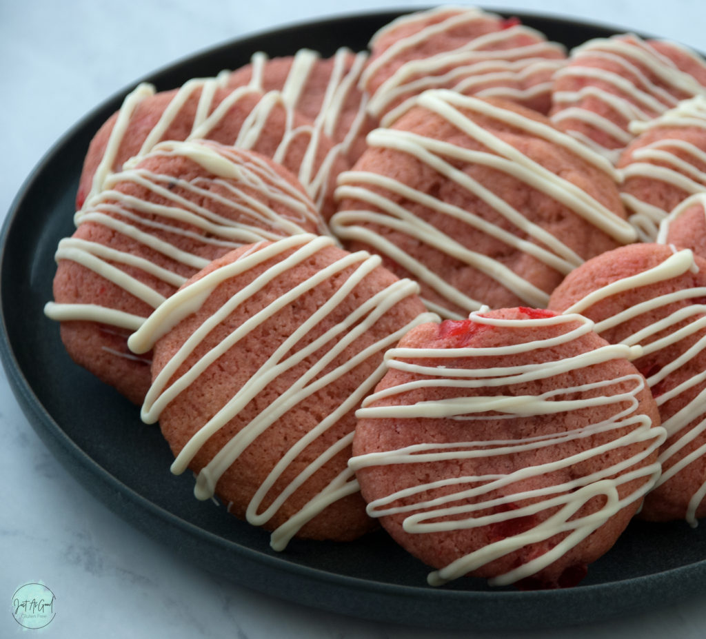 black plate of cherry cookies with white chocolate drizzle