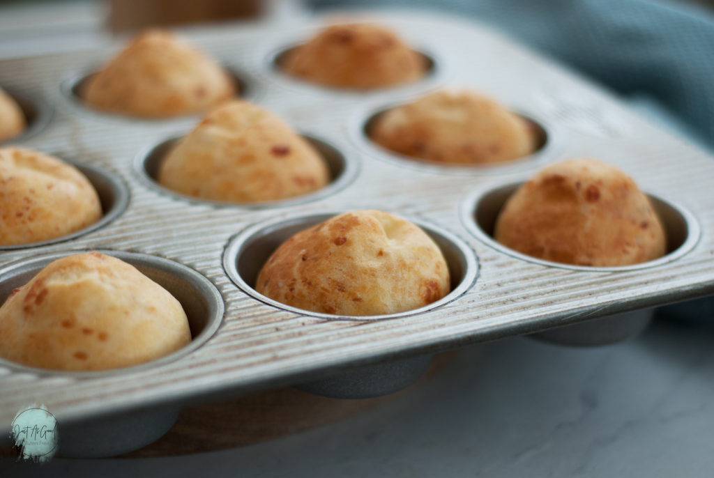 A side view of muffin tin of baked Brazilian cheese bread rolls