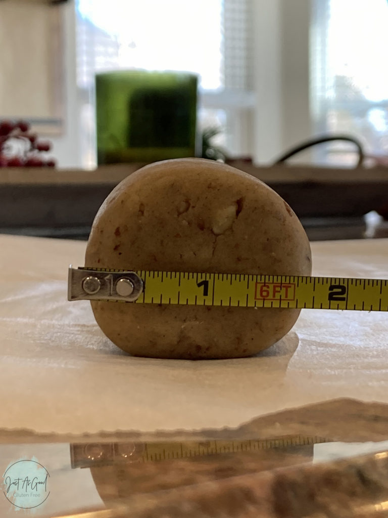 Gluten free pecan shortbread roll of dough with measuring tape measuring 1 and three quarter inch in diameter