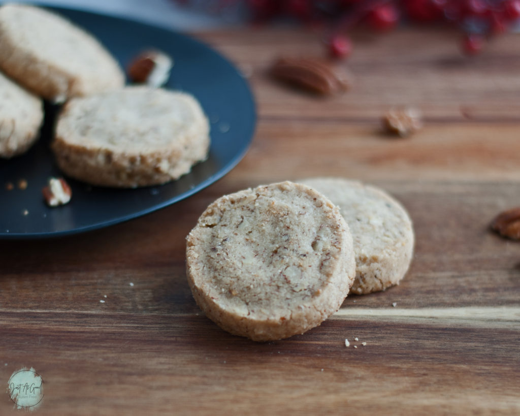 Gluten Free Pecan Shortbread Cookies tilted next to black plate on a wood board