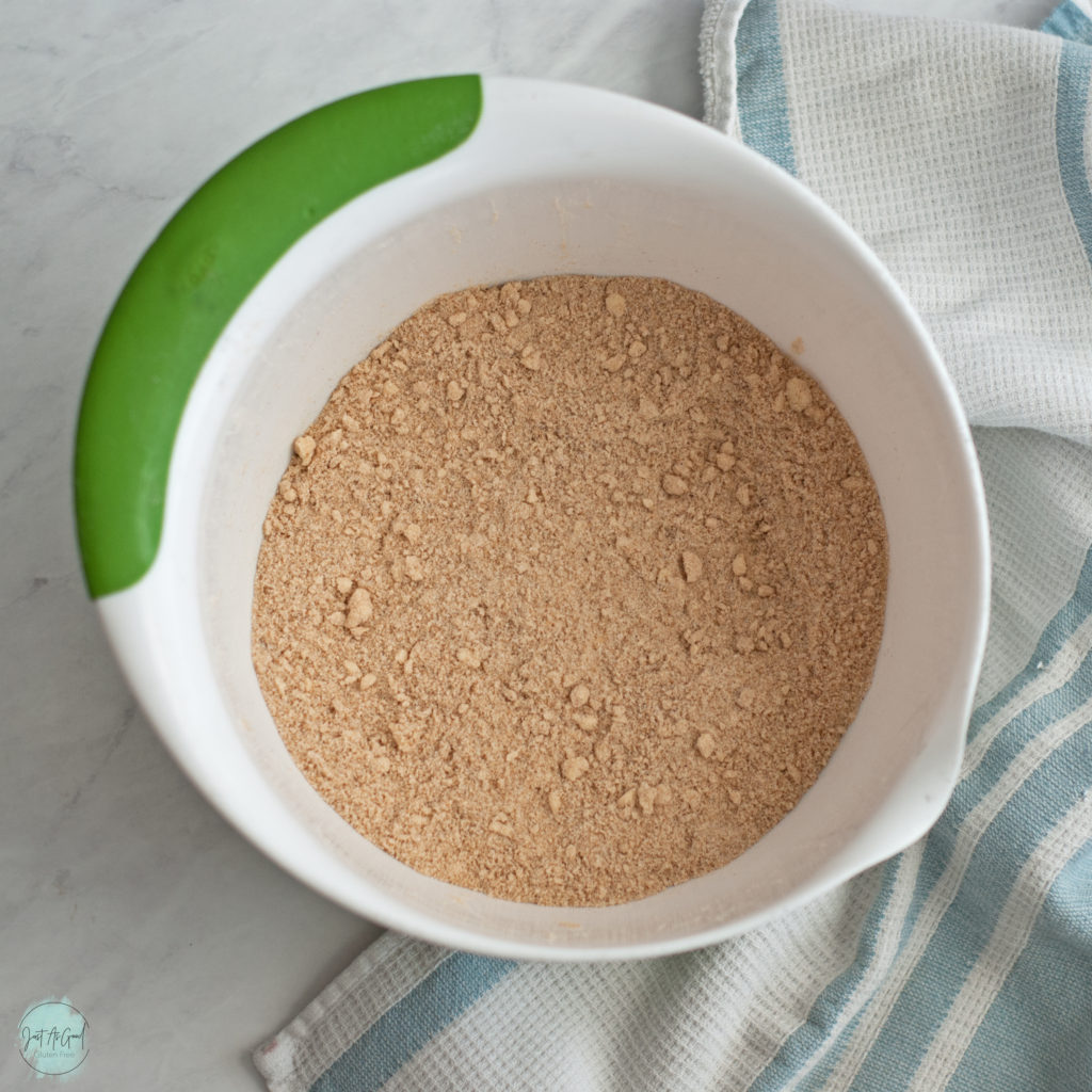 a bowl of gluten free graham cracker flour mixed with butter before liquid