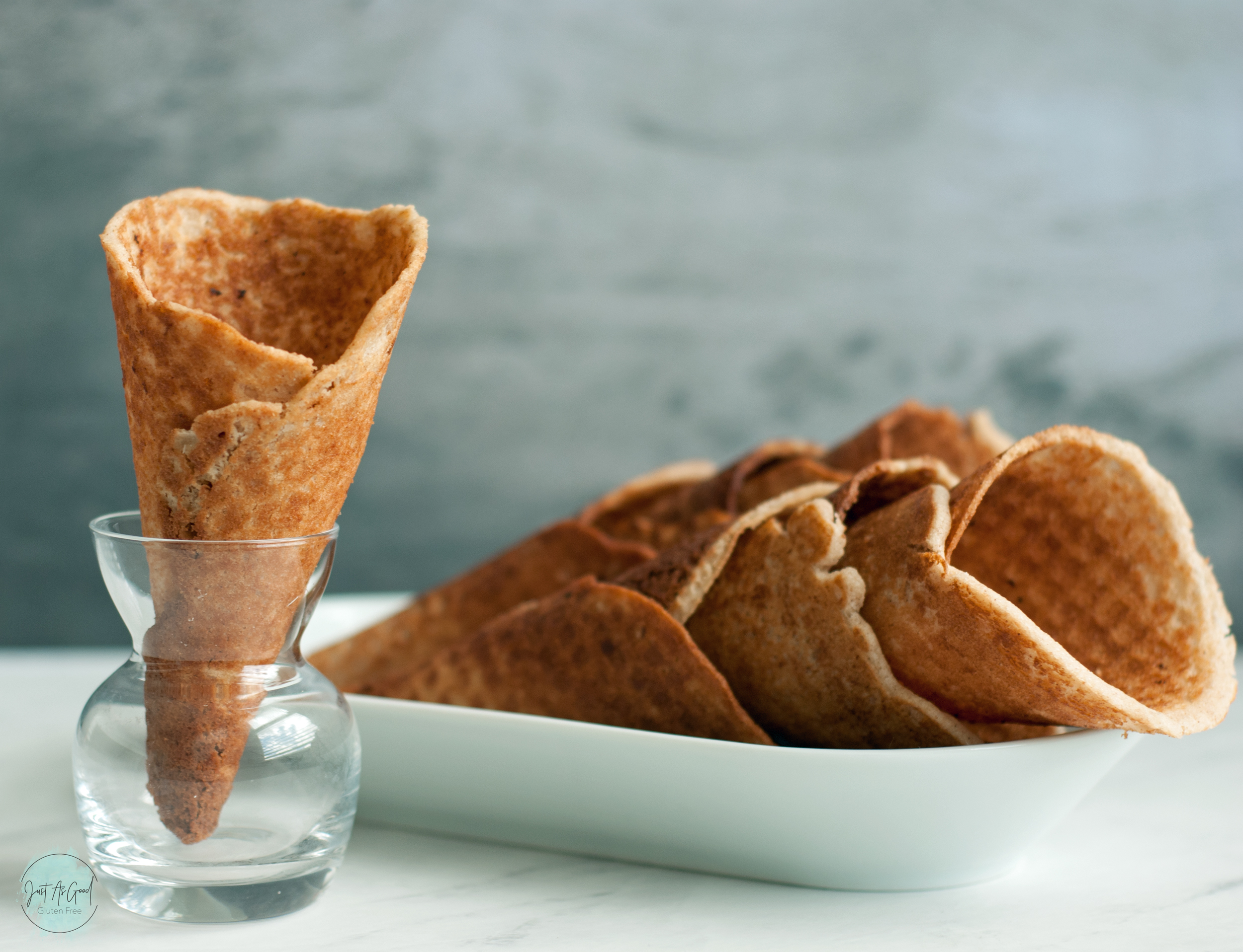 a single waffle cone standing on left with stacked and laying down waffle cones behind