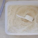40 cup plastic container of gluten free flour blend with measuring cup inside