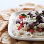 a white plate of seven layer Mediterranean dip with gluten free crackers
