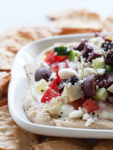 a white plate of seven layer Mediterranean dip with gluten free crackers