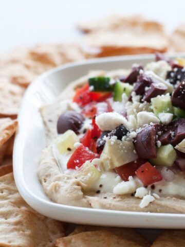 a white plate of seven layer Mediterranean dip with gluten free crackers